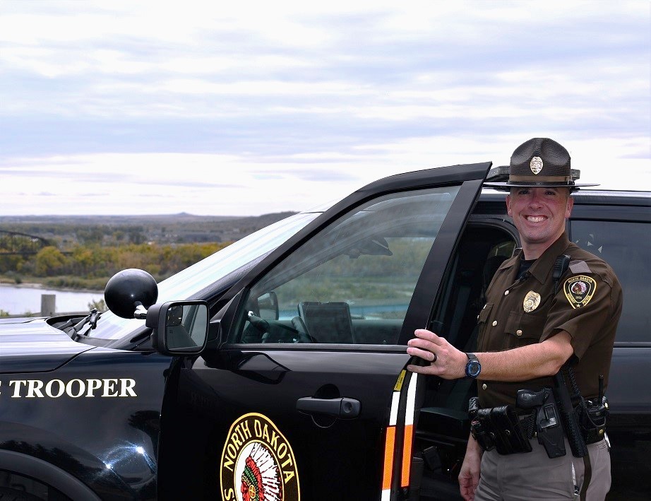 Trooper Michael Hayen standing by his NDHP vehicle overlooking the Missouri River.