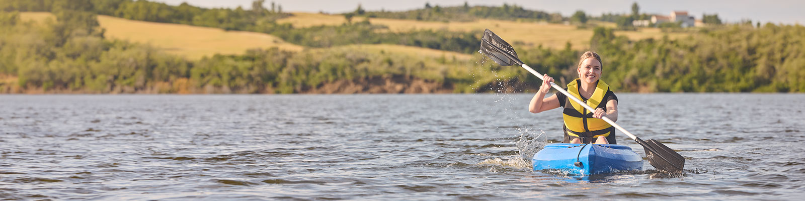 Young woman kayaks on a beautiful summer day at Harmon Lake near Mandan.