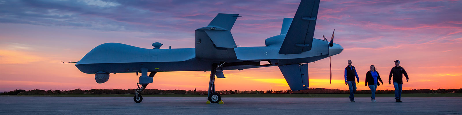 The sun sets behind a parked predator drone. 