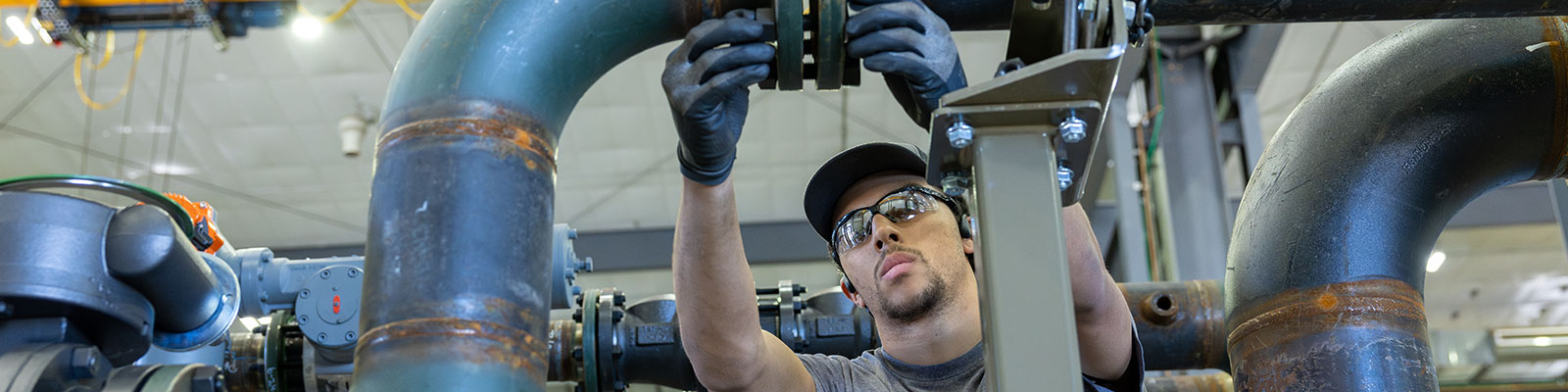 Manufacturing worker checks pipe fitting.