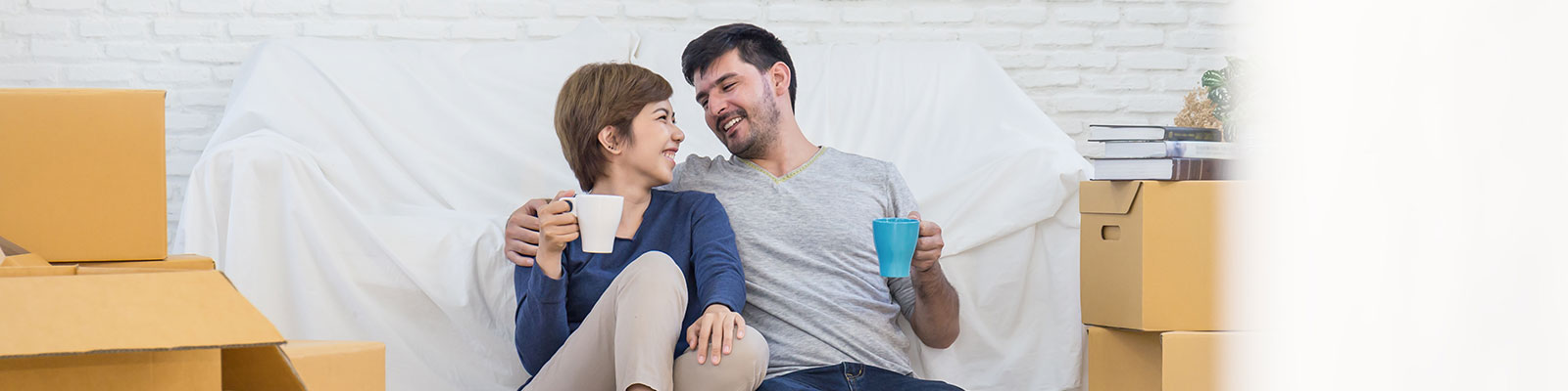 Couple sits on the floor between boxes, taking a break from packing.